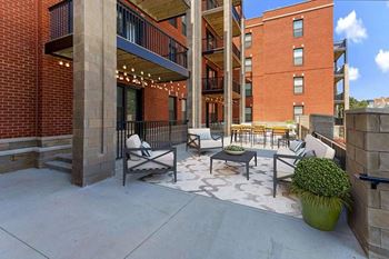 A patio with a table and chairs is surrounded by brick buildings